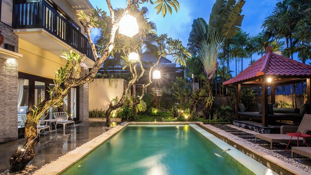 A swimming pool with lounge chairs and a gazebo, surrounded by tropical plants and a building with a balcony. - 2BR Private Pool Tiga Samudra Villa (badung)