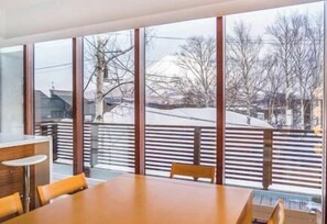 Un espace repas moderne avec une grande fenêtre, une table en bois et des chaises.