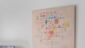 Un soggiorno moderno dal design minimalista, con una TV a schermo piatto, un tavolino in legno e un quadro astratto dai colori vivaci appeso alla parete.
