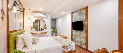A hotel room with a bed, a desk with a chair, a television, and a wall with a decorative pattern.