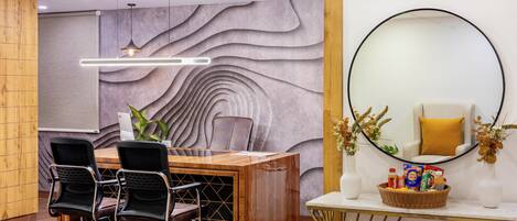 Una moderna recepción con un mostrador de madera, sillas negras, un espejo grande y una pared con textura ondulada.