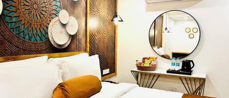 A hotel room with a bed, a bedside table with a basket of snacks, a round mirror, and a wall with intricate wood paneling.
