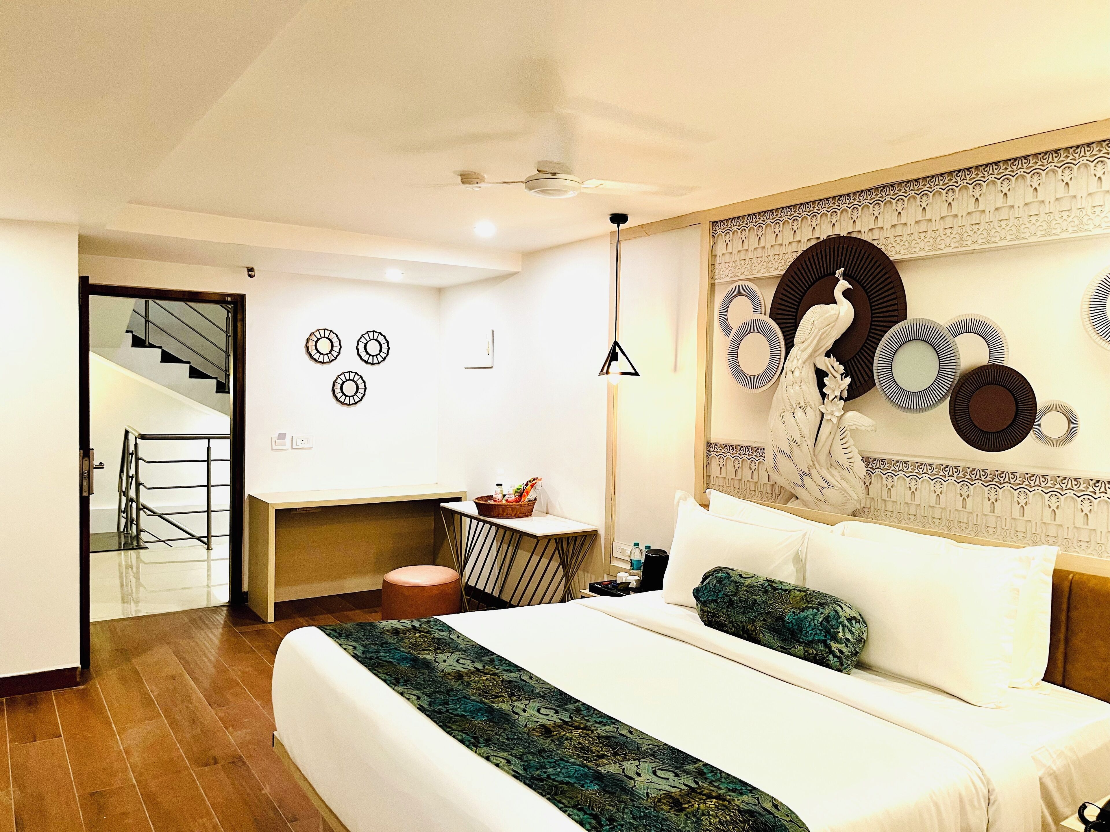 Habitación de hotel moderna con una cama grande, un pequeño rincón de descanso y una escalera que conduce a un piso superior.