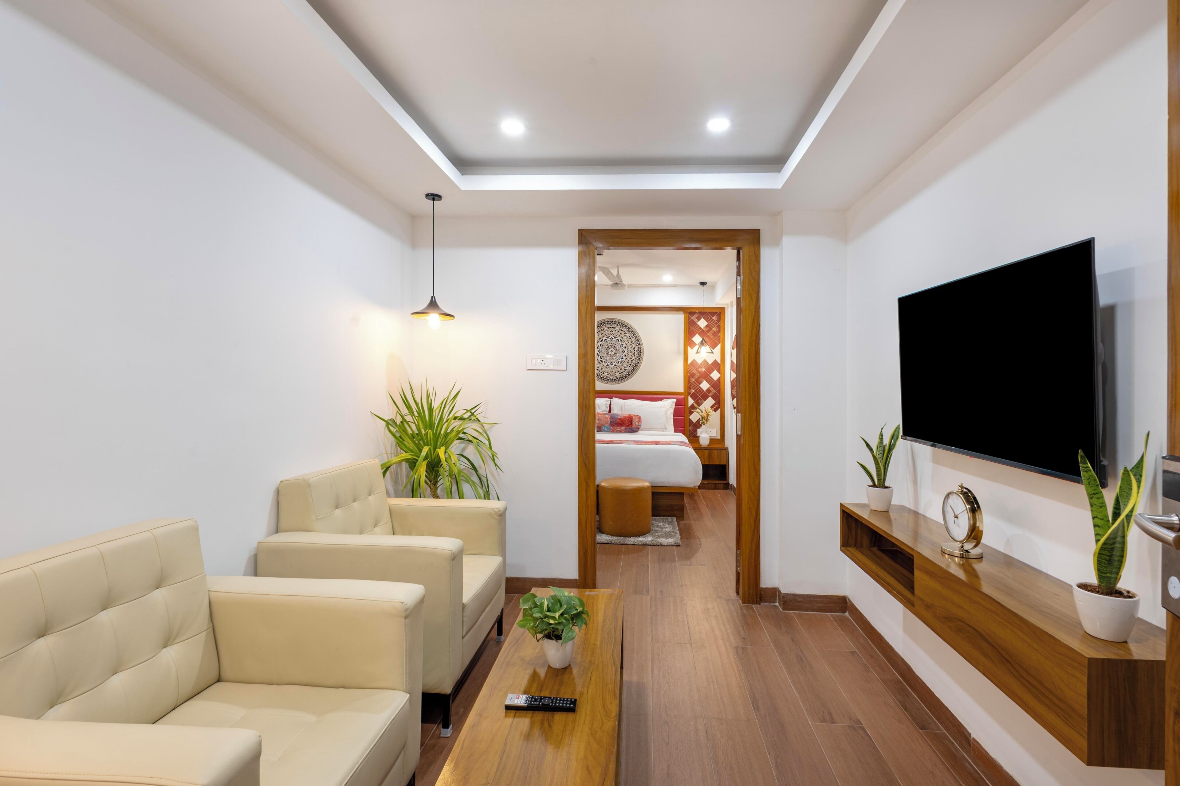 A modern living room with a sofa, a coffee table, a TV, and a hallway leading to a bedroom.