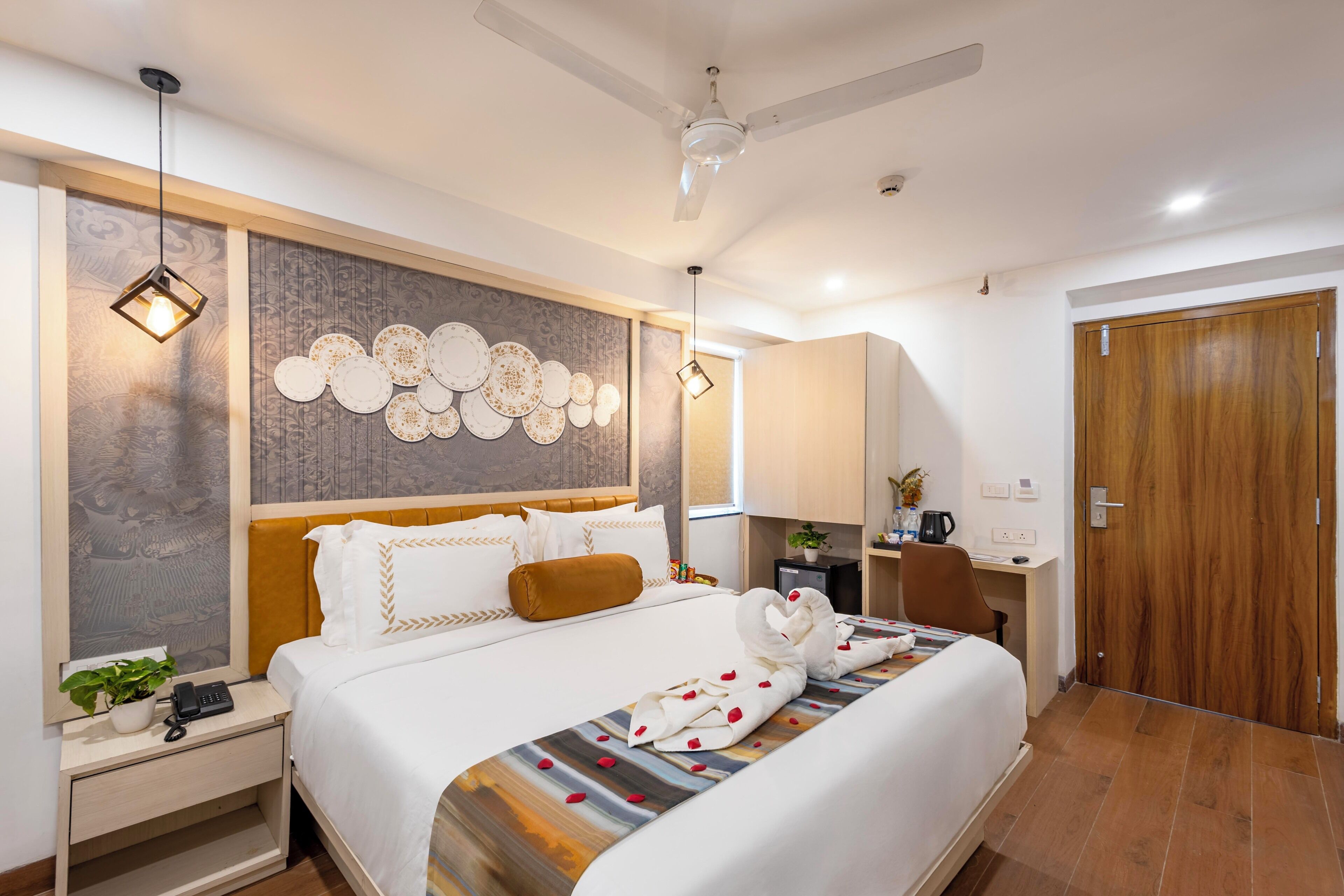 A hotel room with a bed, bedside table, desk, and wardrobe.