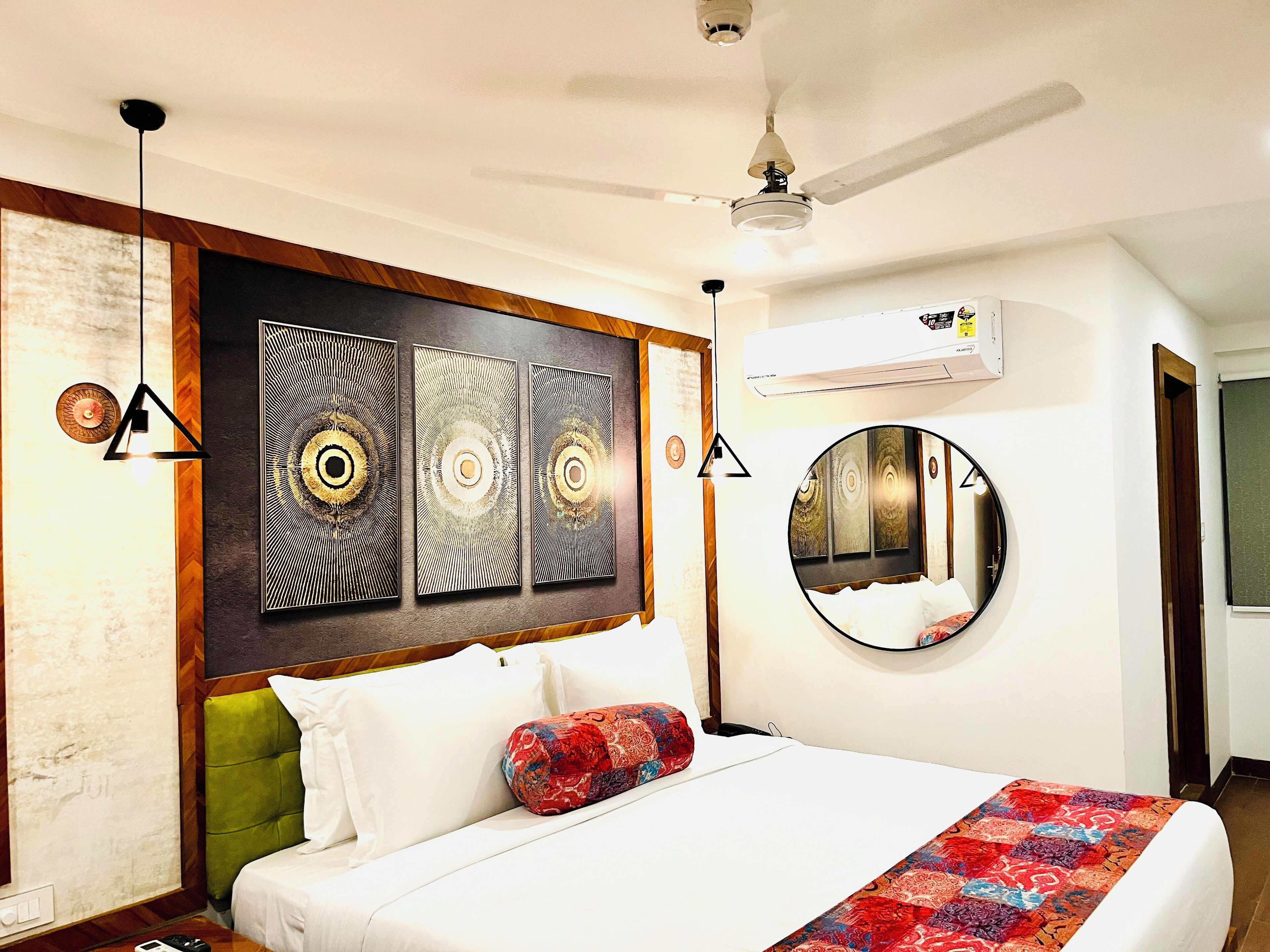 A hotel room with a bed, a round mirror, and a ceiling fan.