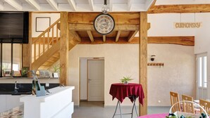 A hotel interior with a wooden staircase, a reception desk, a dining area with a red tablecloth, and a clock on the wall. - Family Cottage in the Countryside (Noyant-Villages)