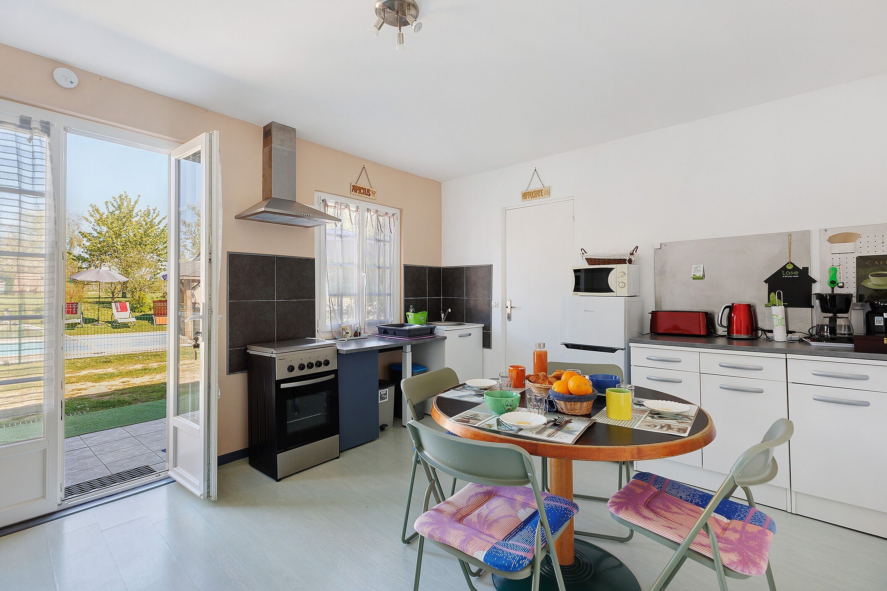 A modern kitchen with an open layout, a dining area with chairs, and a view of the outdoors.