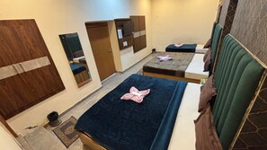 Una habitación de hotel con dos camas, un espejo, un televisor y una mesita.