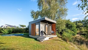 Ein modernes, kompaktes Haus mit einer kleinen Veranda, einem Trampolin und einem gepflegten Rasen.