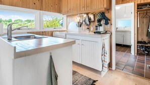 Eine moderne Küche mit Holzverkleidung, einer großen Kochinsel mit Spüle und Blick auf Grünfläche.