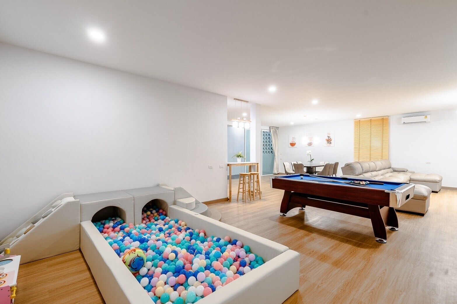 A room with a pool table, a ball pit, and a sofa.