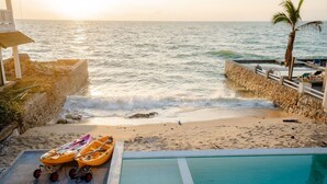 Vistes a la platja amb una piscina, un caiac i un petit vaixell.