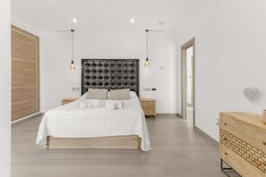 A bedroom with a tufted headboard, a wooden nightstand, a wooden dresser, and a view of the hallway. - Country House in a Top Location with Mountain Views, Wi-Fi and Air Conditioning (Coin)