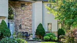A stone pathway leading to a house with a stone facade and a small front porch.