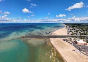 An aerial view of a coastal area with a beach, a pier, and a residential area. - Expansive South Haven Estate | Pool | Firepit (South Haven)