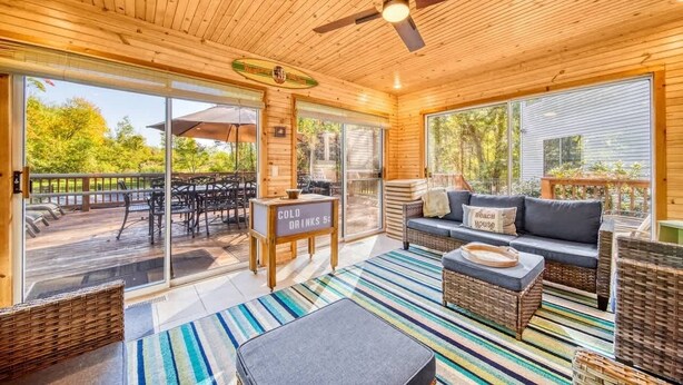 A wooden interior with a ceiling fan, a sofa, a table, and a sign that reads "COLD DRINKS 5¢".