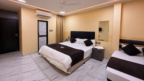 A hotel room with a large bed, a smaller bed, an air conditioning unit, a nightstand, and a mirror on the wall. - Hotel Roshan (Ujjain)