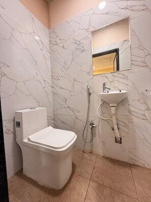 A bathroom with a toilet, sink, and shower. - Hotel Roshan (Ujjain)