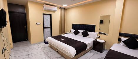 A hotel room with a large bed, bedside tables, a ceiling fan, and an air conditioning unit.
