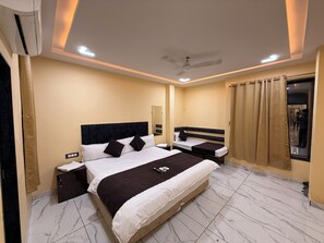 A hotel room with a large bed, two bedside tables, a ceiling fan, and a window with curtains. - Hotel Roshan (Ujjain)