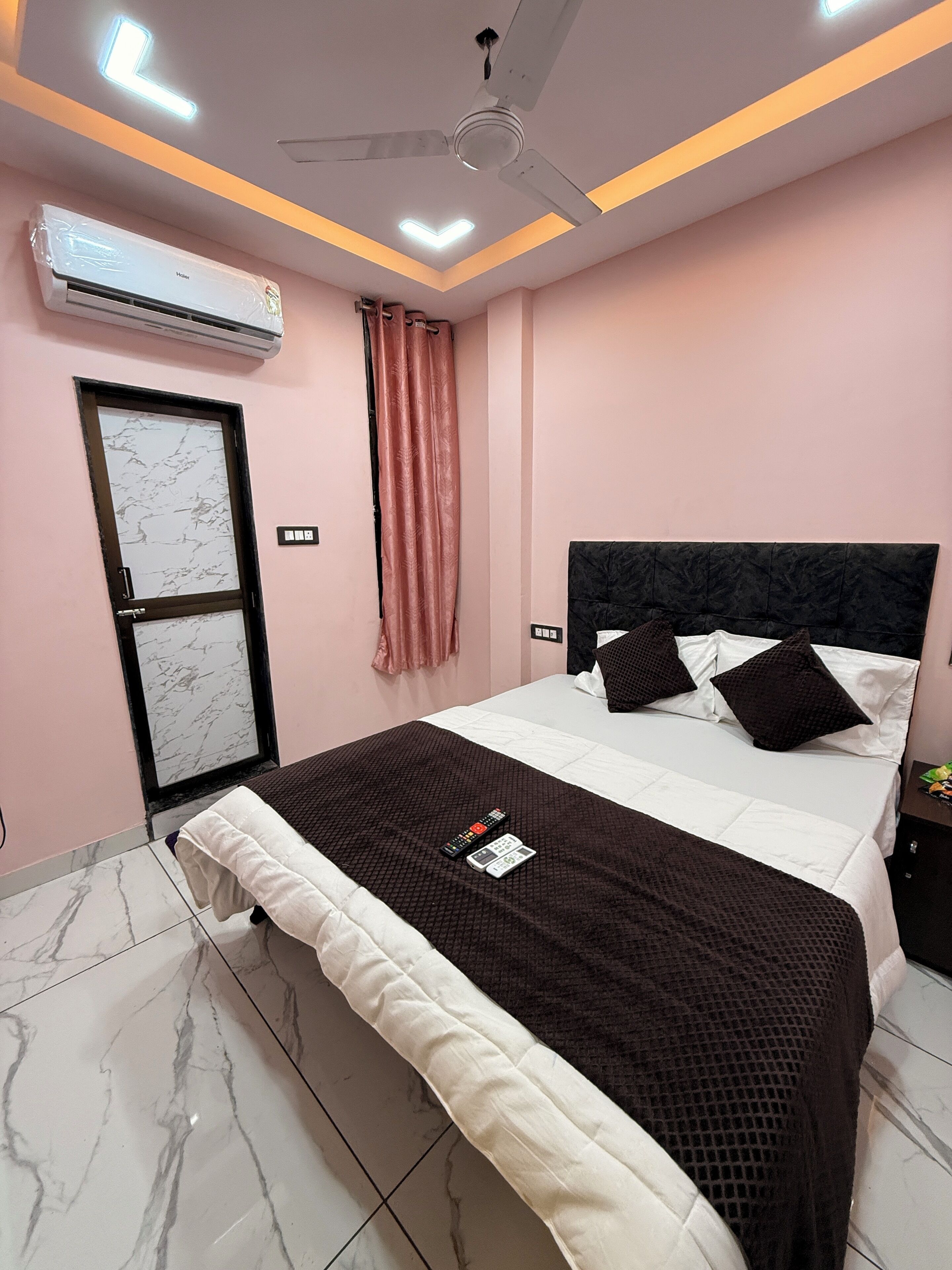A modern bedroom with a bed, a ceiling fan, an air conditioner, and a door with a marble pattern.