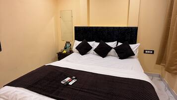 Quarto de hotel com uma cama grande, uma mesa de cabeceira, um espelho e uma luminária no teto.