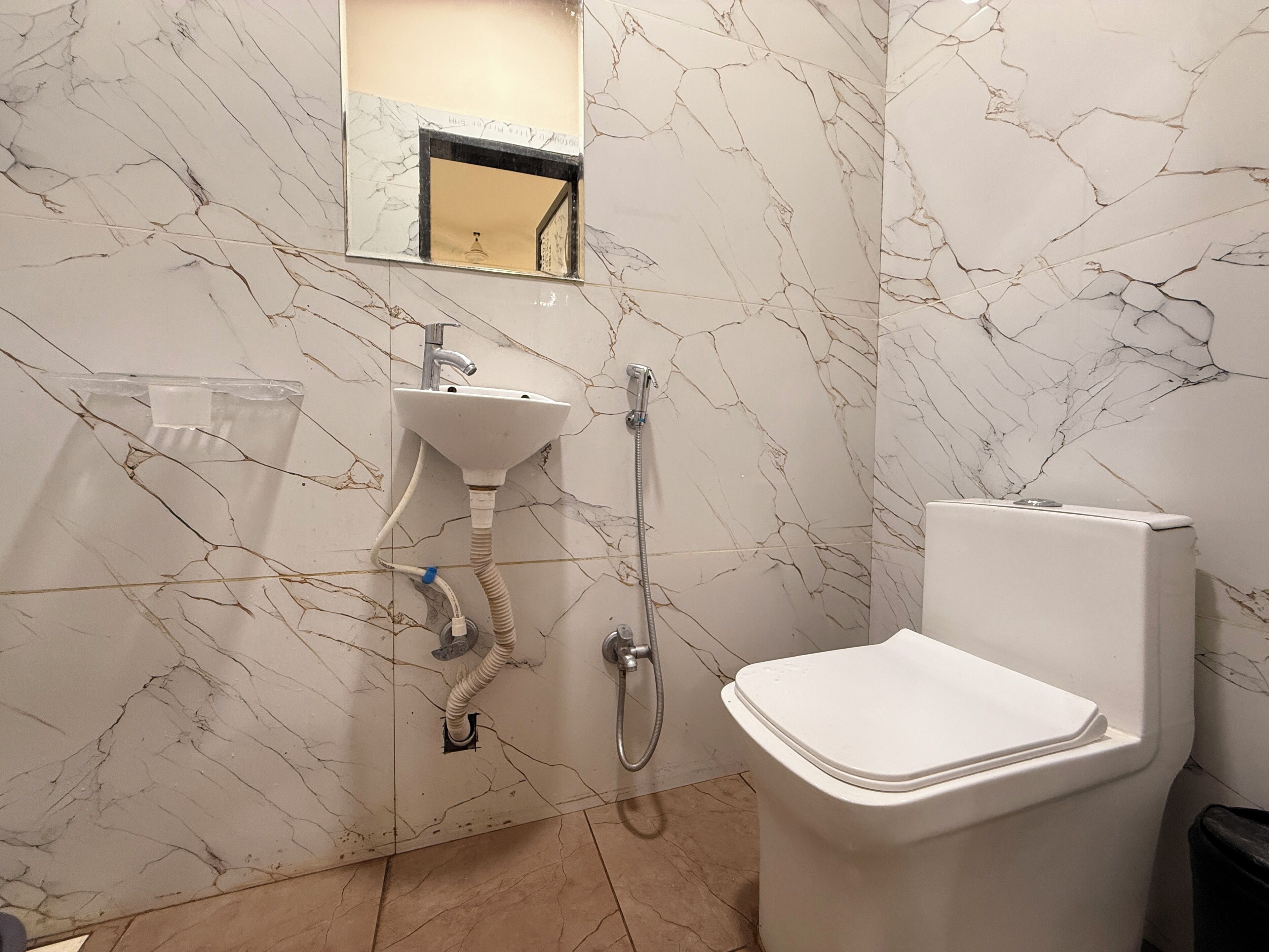 A bathroom with a sink, mirror, shower, and toilet.
