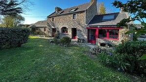 A stone house with a red door and a small garden.