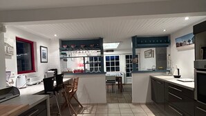 A modern kitchen with a central island, a dining area, and a view of the living room.