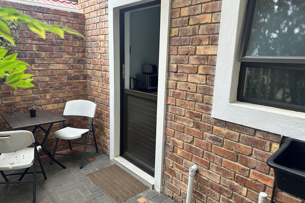 Un pequeño espacio al aire libre con pared de ladrillo, puerta corredera y ventana.