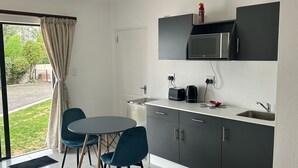 A compact kitchen with a dining area, a microwave, a kettle, and a sink.