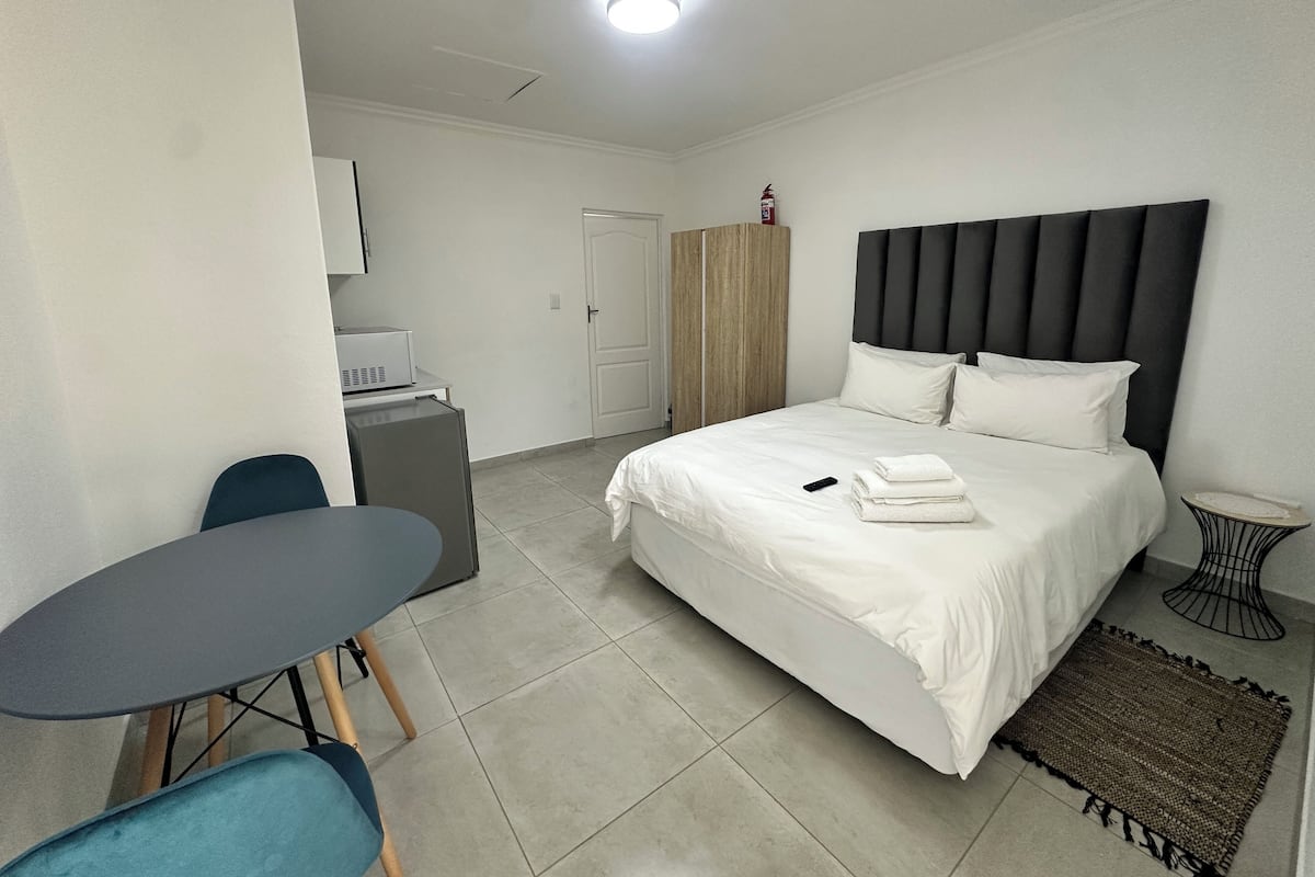 Habitación de hotel con cama, escritorio, silla, armario y una mesita.