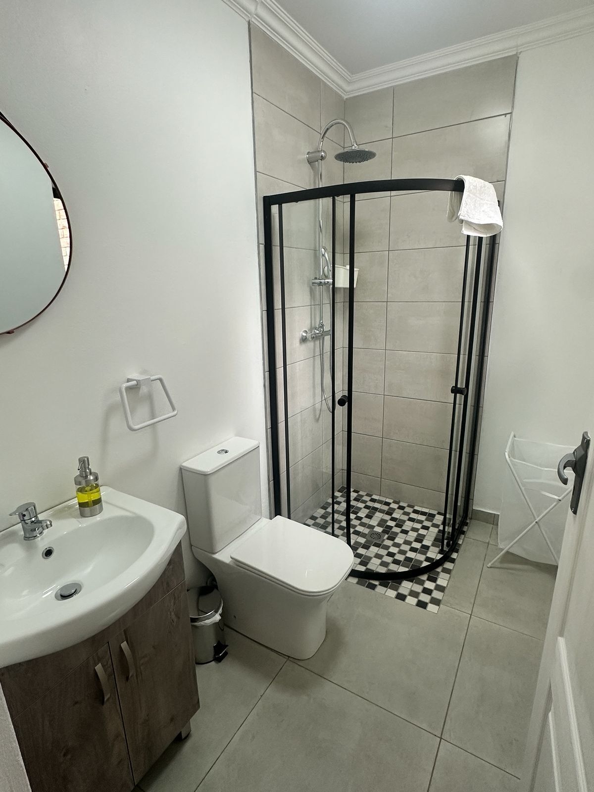 Un baño con ducha, lavabo, inodoro y espejo.