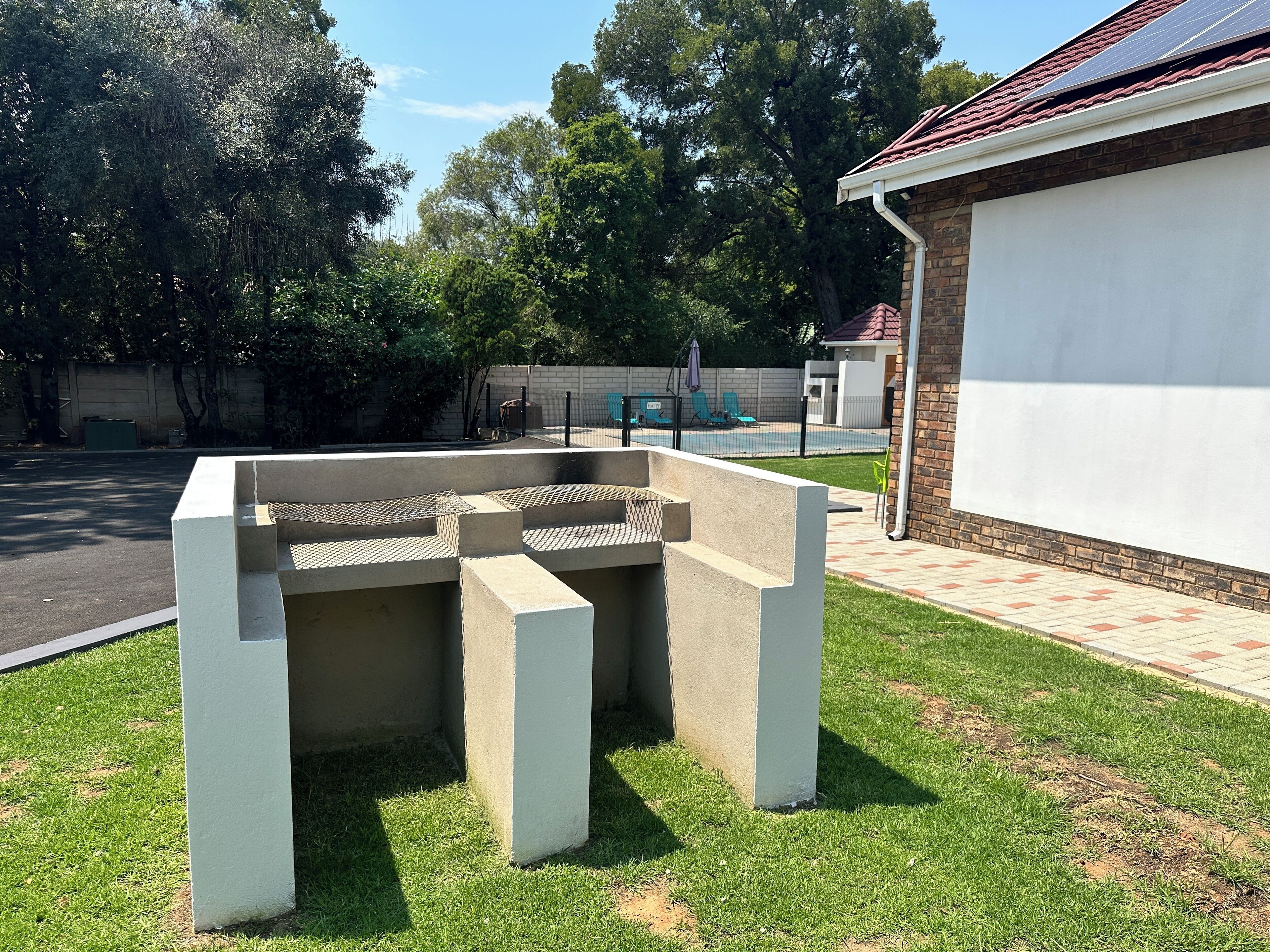 Un espace extérieur aménagé avec des sièges, une structure en béton et une piscine en arrière-plan.