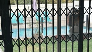 A room with a view of a swimming pool through a metal gate.