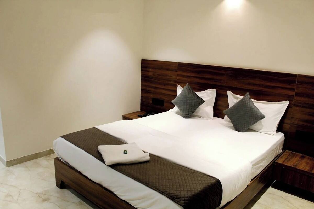 A neatly made bed with a wooden headboard, white bedding, and two pillows.