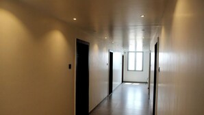 A long, narrow hallway with doors on both sides, leading to rooms. - Aatithya Residency (Rajgurunagar)