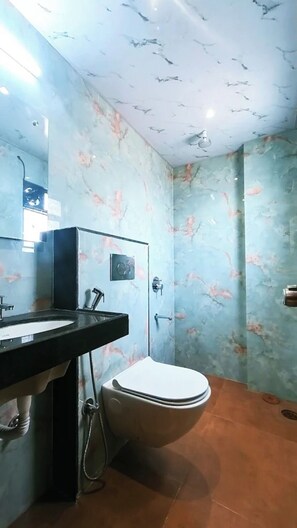 A bathroom with a marble wall, a sink, a toilet, and a shower. - Aatithya Residency (Rajgurunagar)