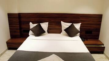 A neatly made bed with a wooden headboard, two pillows, and a bedside table with a remote control.