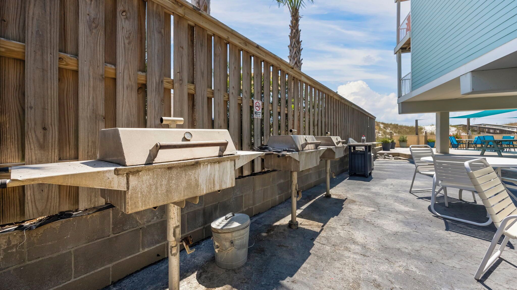 An outdoor patio area with a barbecue grill, seating, and a wooden fence.