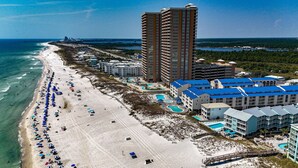 Un complexe hôtelier de bord de mer doté d’une longue plage de sable, de plusieurs piscines et d’immeubles de grande hauteur.