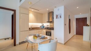 A modern kitchen with white cabinets, a dining table with chairs, and a small refrigerator. - Luxury 1BR in Marina Gate with Infinity Pool (Dubai)
