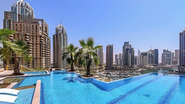 A swimming pool with a cityscape in the background. - Luxury 1BR in Marina Gate with Infinity Pool (Dubai)