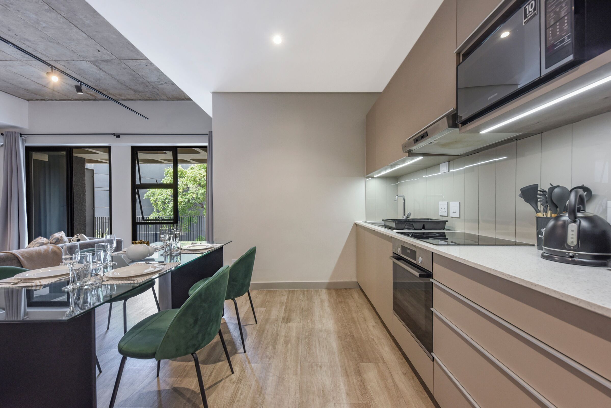 A modern kitchen with a large island, built-in appliances, and a dining area with a glass table and chairs.