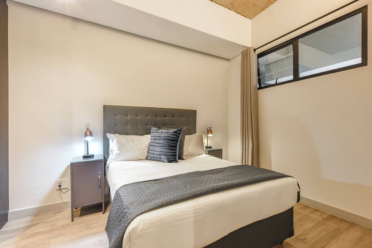 A bedroom with a bed, nightstands, and a window.
