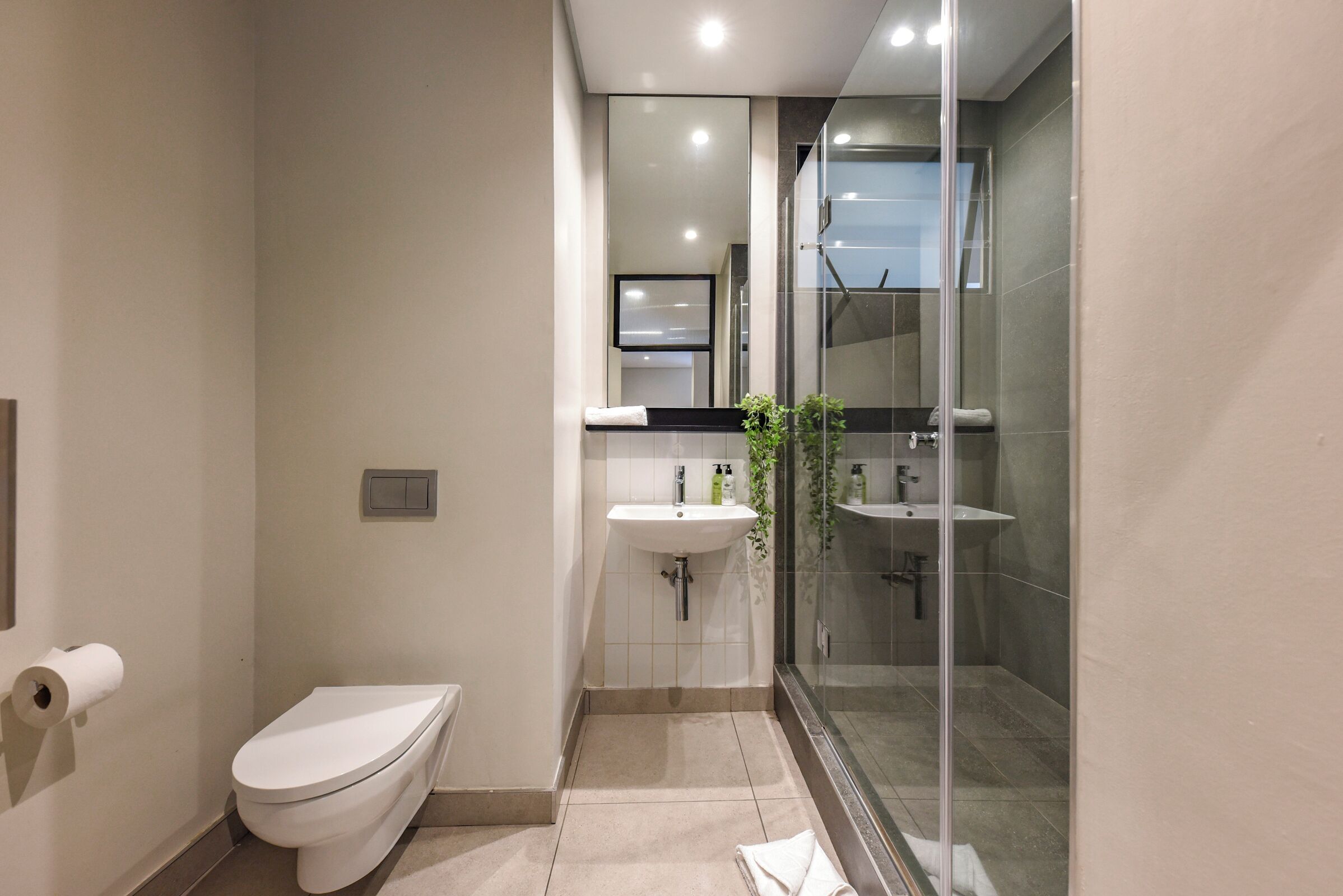 A modern bathroom with a toilet, sink, and glass shower enclosure.