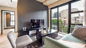 Una sala moderna con un televisor de pantalla plana, una mesa de centro y un sofá.