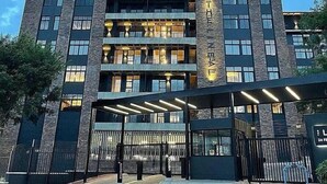Un hotel de varios pisos con un diseño arquitectónico moderno, que cuenta con balcones y una entrada cubierta.