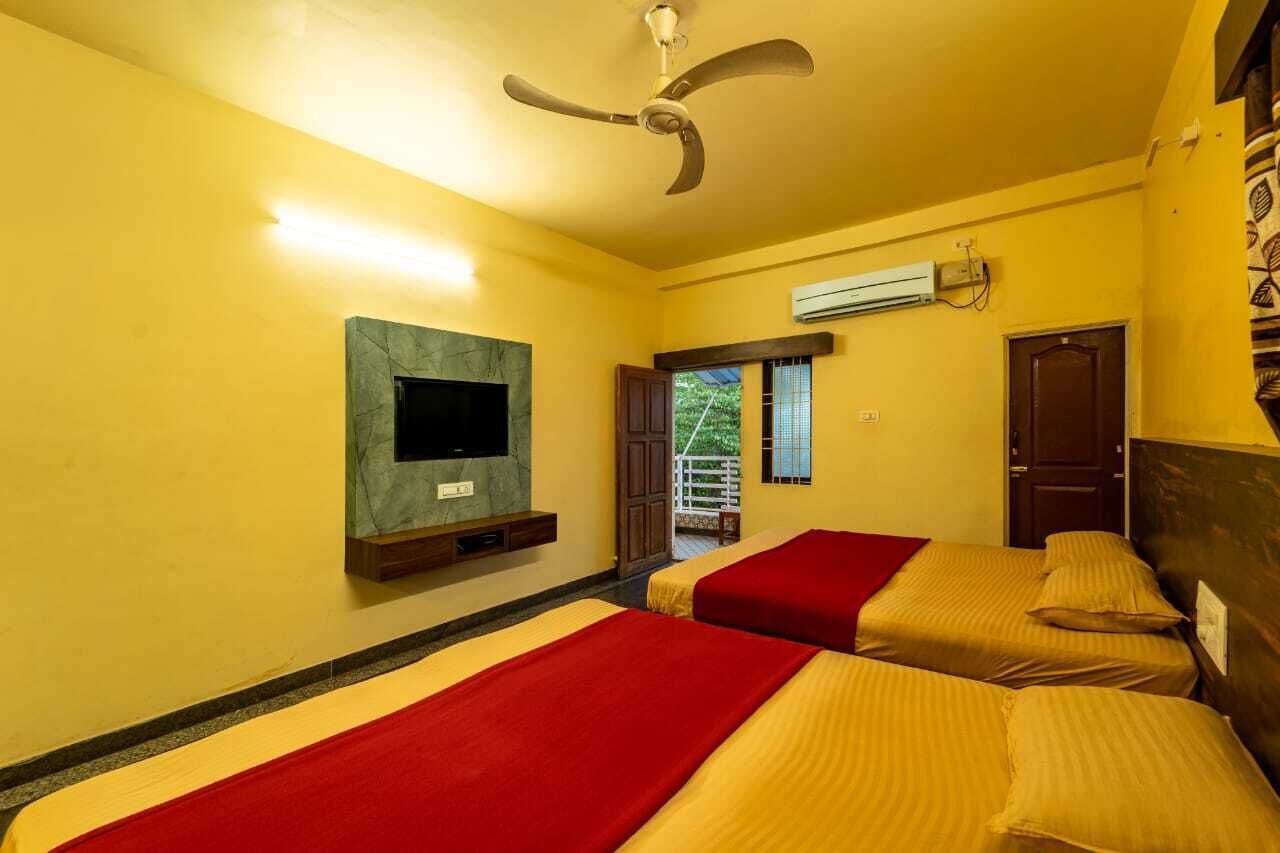 Ein Hotelzimmer mit zwei Betten, einem Deckenventilator, einem Flachbildfernseher und einer Klimaanlage.